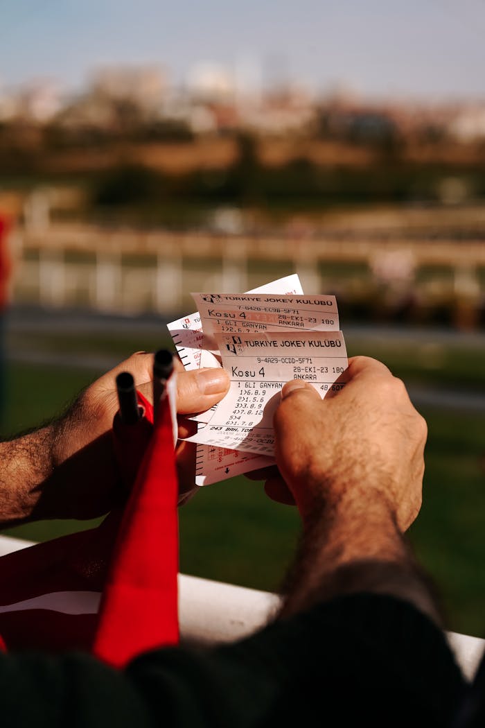 Close-up of a man holding horse racing tickets in Ankara, Türkiye. Vibrant outdoor setting.